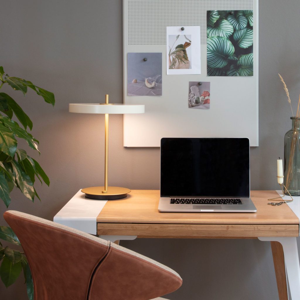 LED-Schreibtischleuchte Asteria table von UMAGE auf einem Holzschreibtisch neben einem geöffneten Macbook im Homeoffice