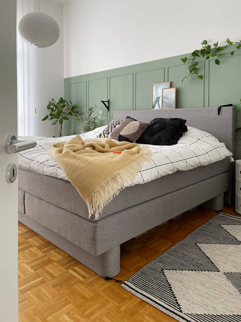 Schlafzimmer mit Boxspring-Bett und hölzerner Wandverkleidung