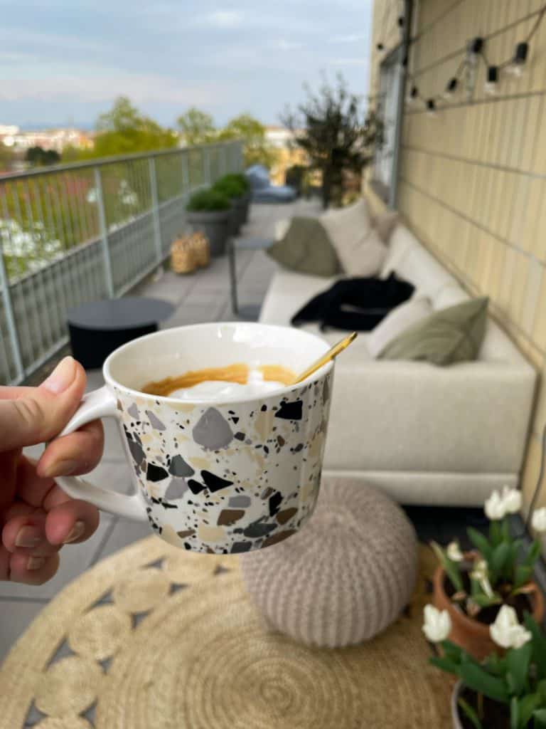 Kaffeetasse auf Dachterrasse mit Sofa und Teppich