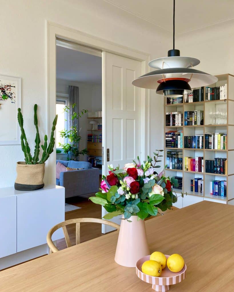 Wohn- und Essbereich mit Bücherregal und Blumenvase mit Schnittblumen