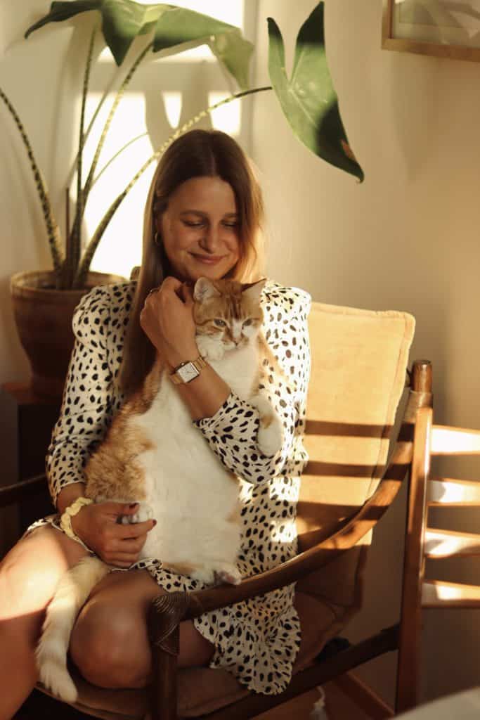 Katrin von @zwischenkatzenundkakteen mit ihrer Katze in ihrem Wohnzimmer (Vintage - Warm & natürlich)