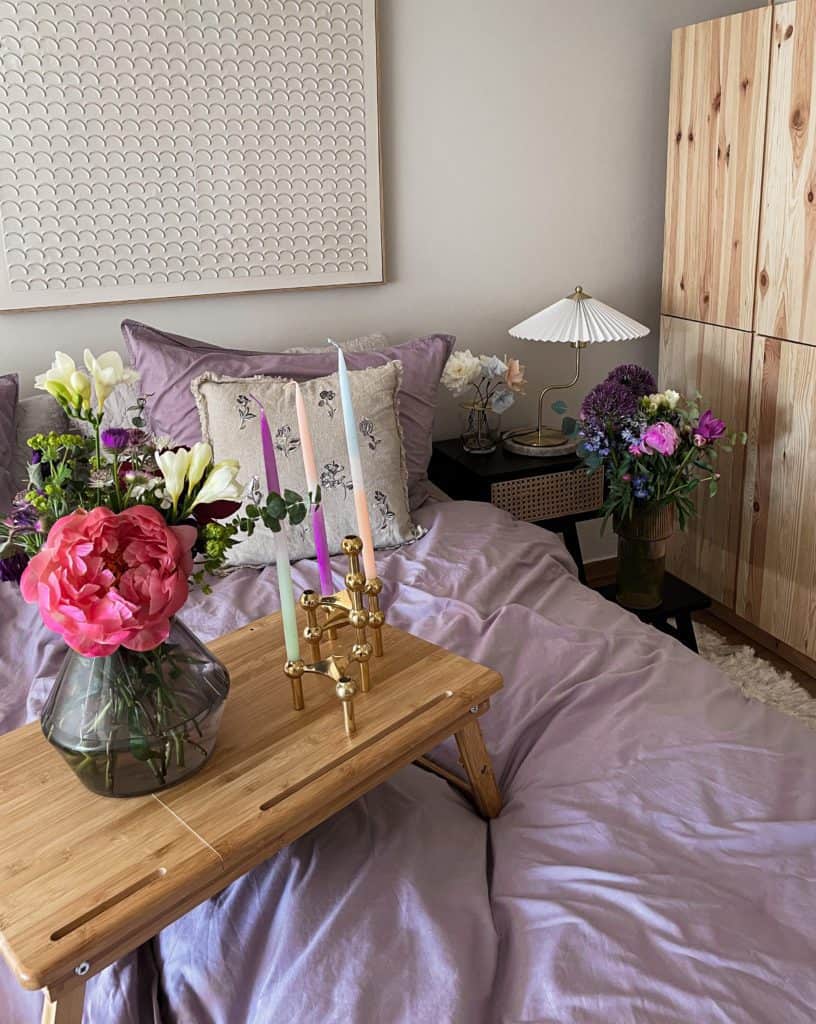 Schlafzimmer im Einrichtungsstil "Vintage-Skandi und ein Hauch Boho" mit Tablette auf dem Kerzenhalter und eine Blumenvase steht. 