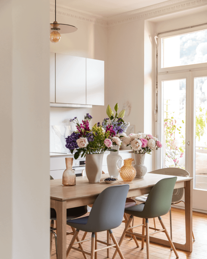 Schnittblumen in Blumenvasen auf Esstisch in heller Altbau-Küche