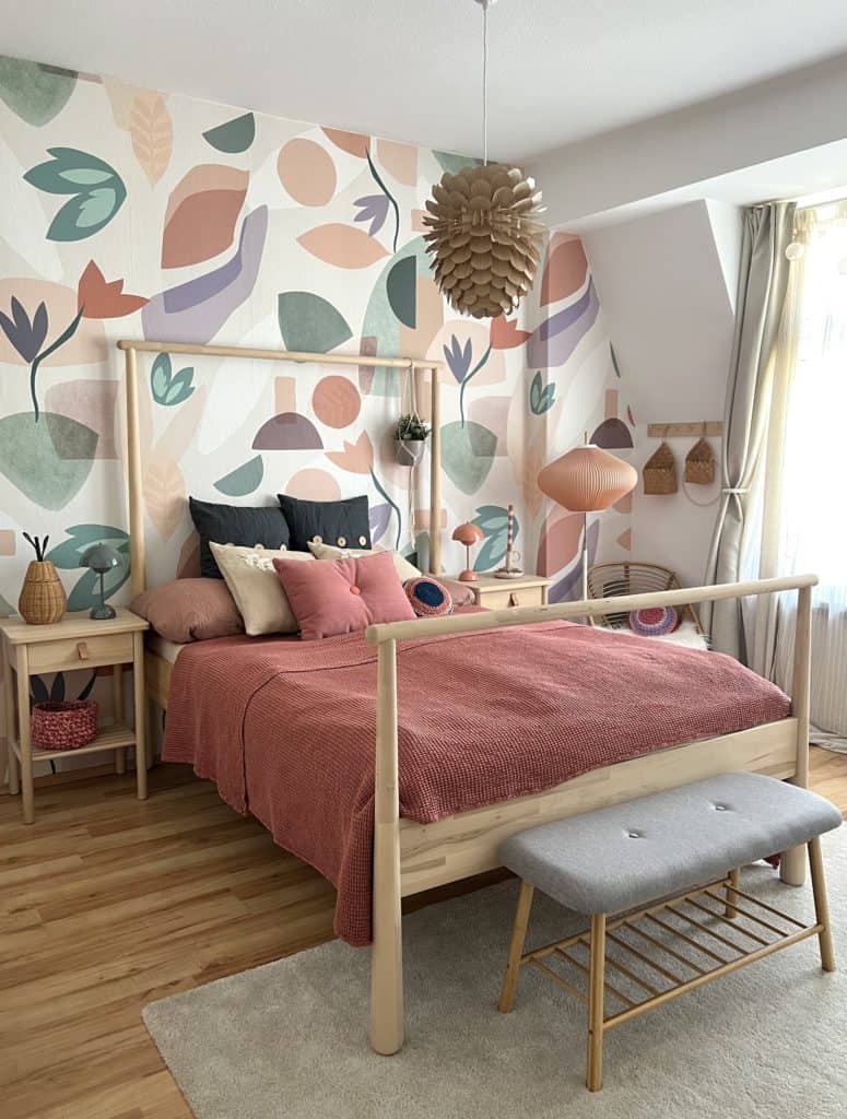 Farbenfrohes Bett in Schlafzimmer mit floraler Tapete 