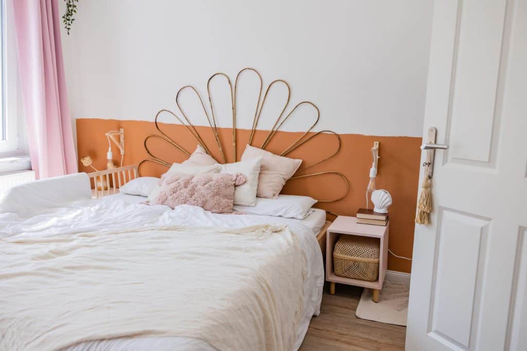 Helles Schlafzimmer mit Bett im Boho Stil und orangener Wandfarbe im Sockelbereich