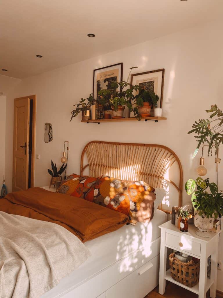 Schlafzimmer mit Holzbett im Boho-Look und vielen Zimmerpflanzen