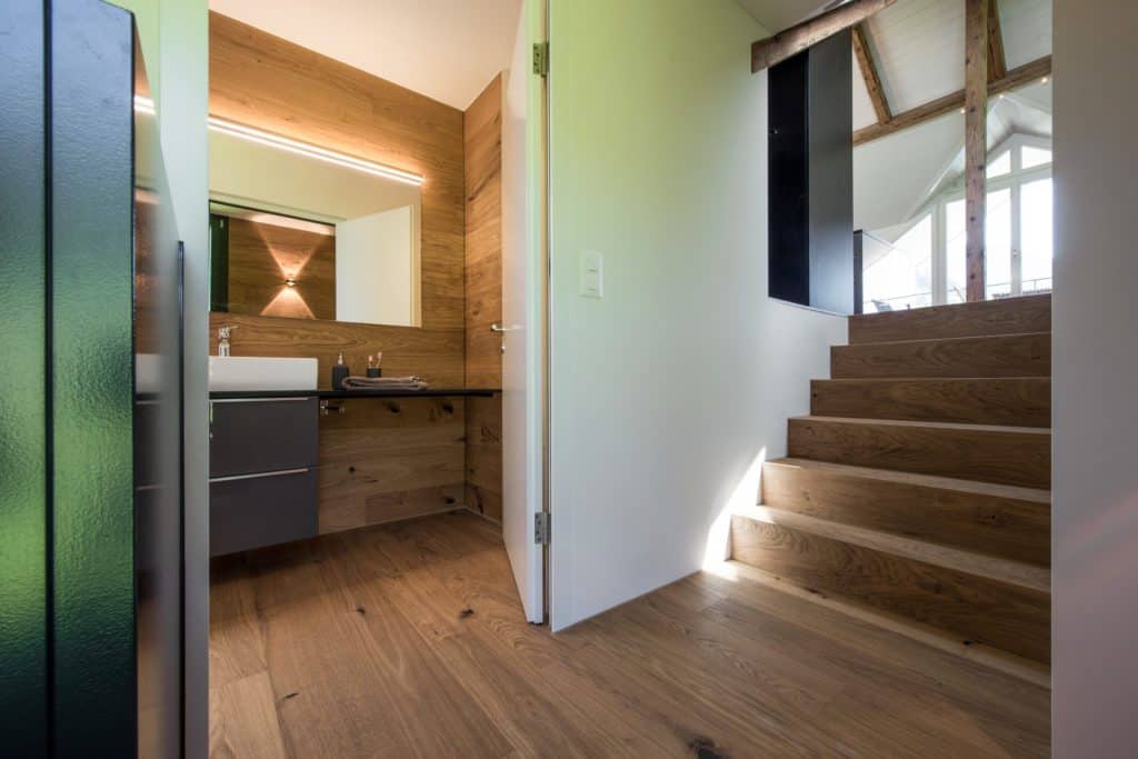 Blick in offenes Badezimmer der Ferienwohnung, das über eine mehrstufige Treppe aus Holz erschlossen wird. 