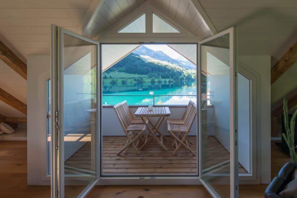 Das Haus am See - Ausblick aus dem Dachgeschoss aus geöffneter Balkontür.  auf das blau-grüne Wasser