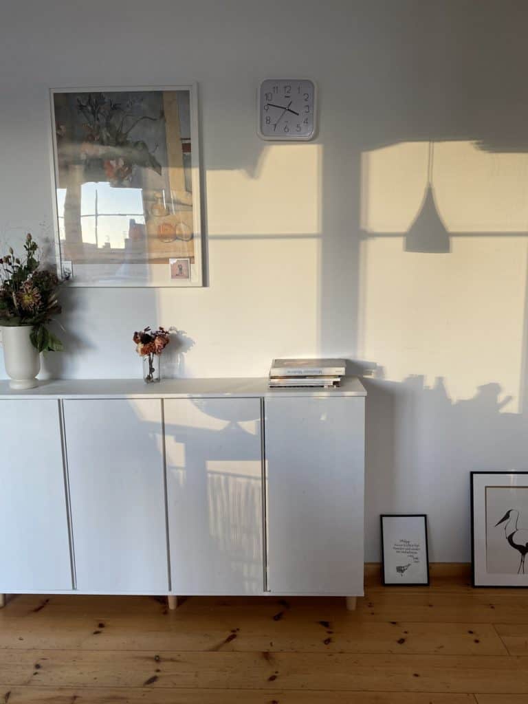 Sideboard aus weiß beschichtetem Holz mit Blumenvasen