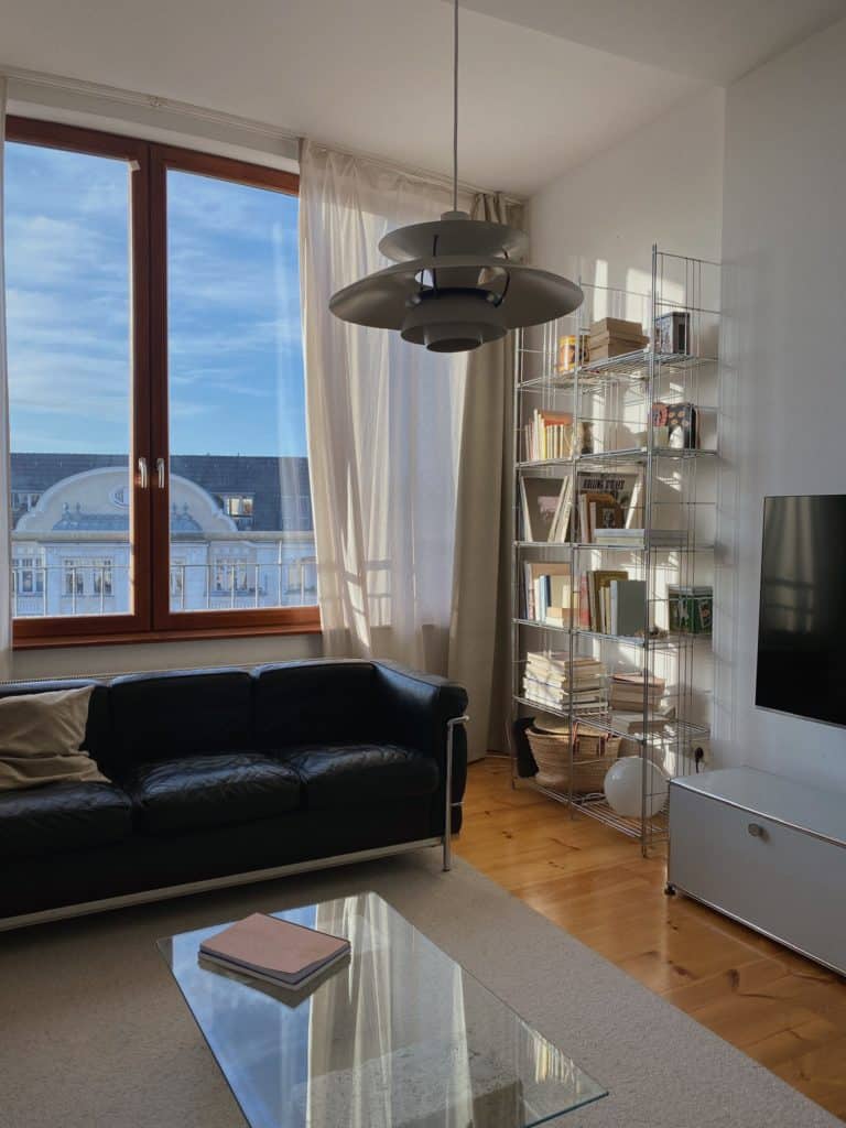 Minimalistische und mediterrane Einrichtung - Wohnzimmer mit schwarzer Leder-Couch und Regal aus Metall-Draht neben USM Haller Lowboard
