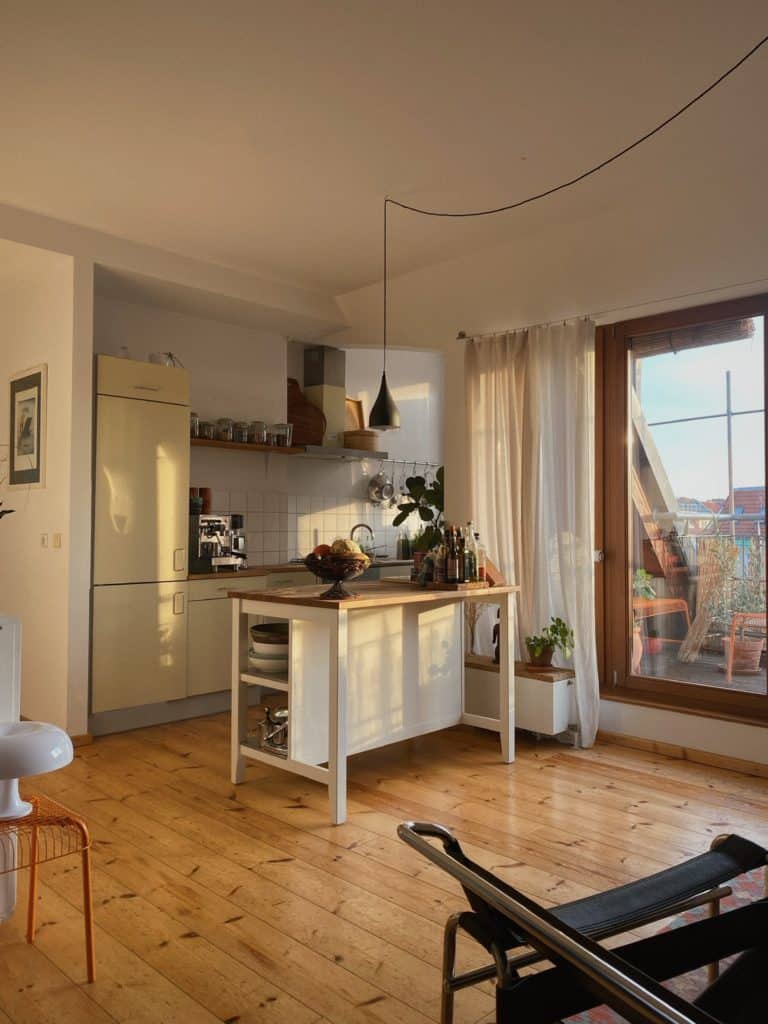 Offene Wohnküche mit Kochinsel in Dachgeschosswohnung mit Dielenboden