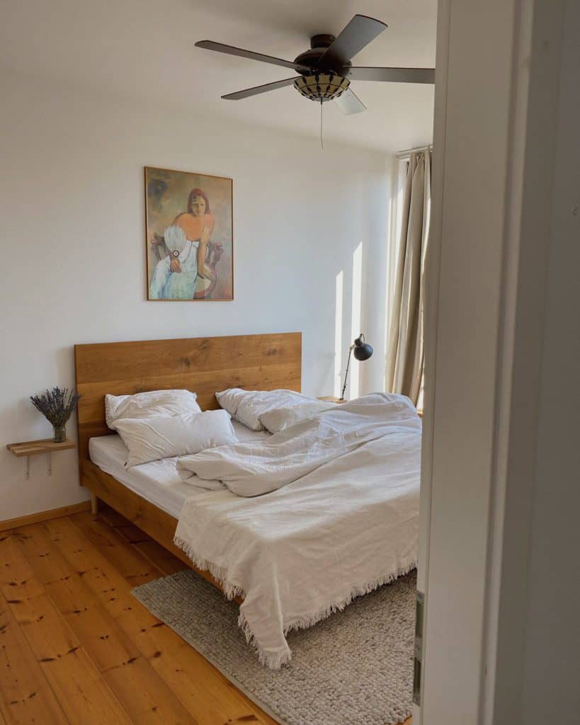 Schlafzimmer mit Holzbellt und heller Bettwäsche
