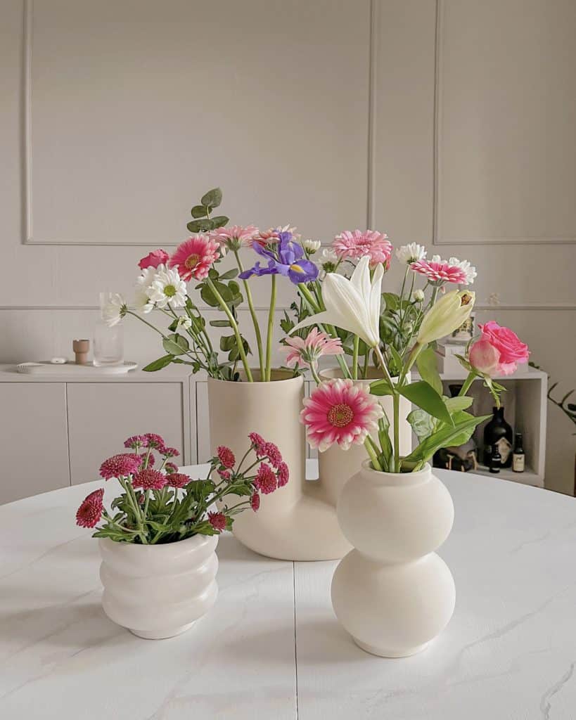 Blumenvasen mit frischen Blumen auf Tischplatte in Marmor-Optik