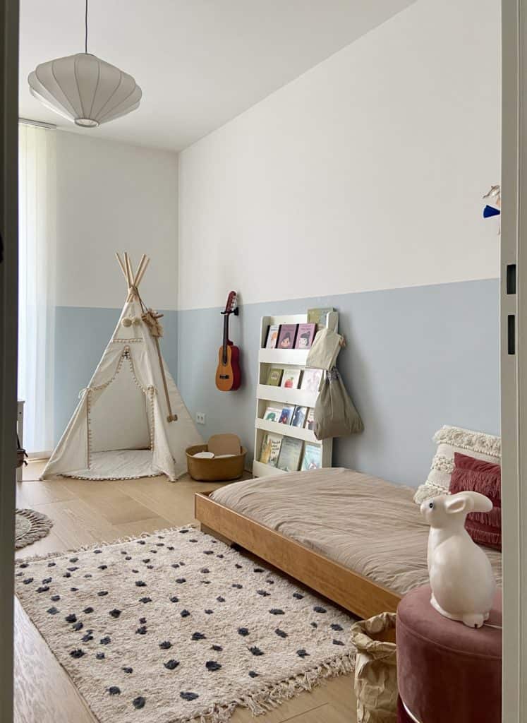 Helles Kinderzimmer mit Tippie und Bücherregal und tiefem Bett