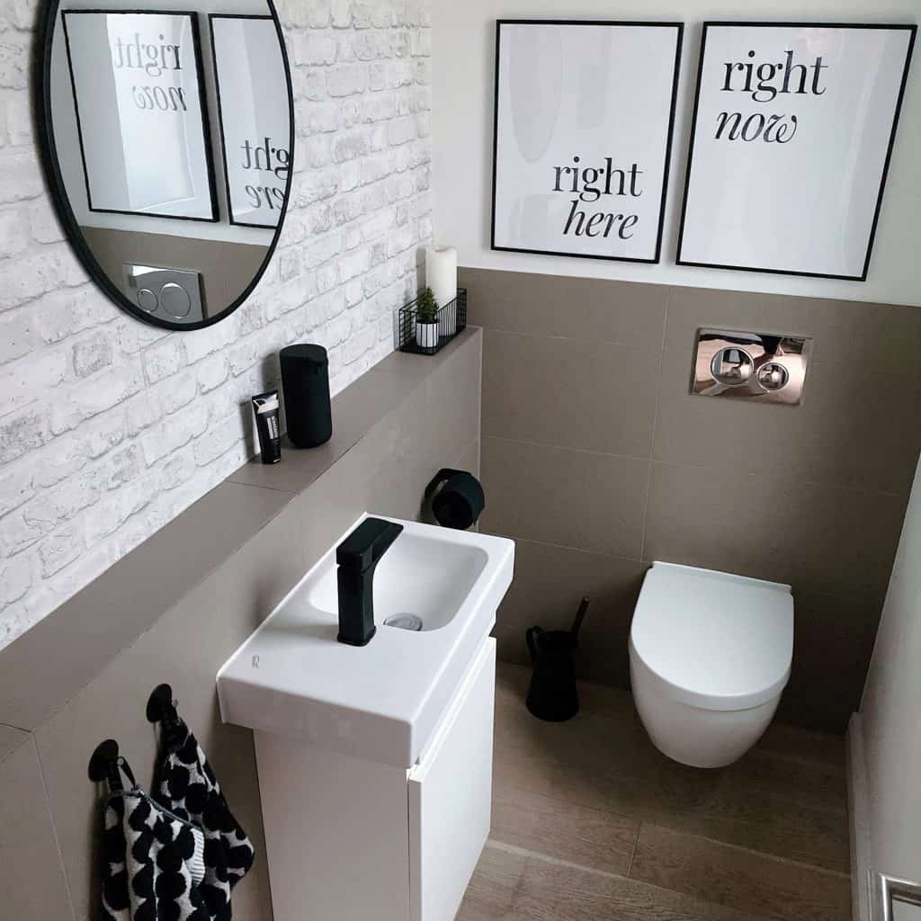 Soft Scandi und Industrial Minimalism - Gäste-WC mit weißen Keramiken und schwarzer Armatur. Die Wände sind halbhoch mittelgrau gefliest. Eine Wand ist in Fliesenoptik ausgeführt, die andere  verputzt und weiß gestrichen. 